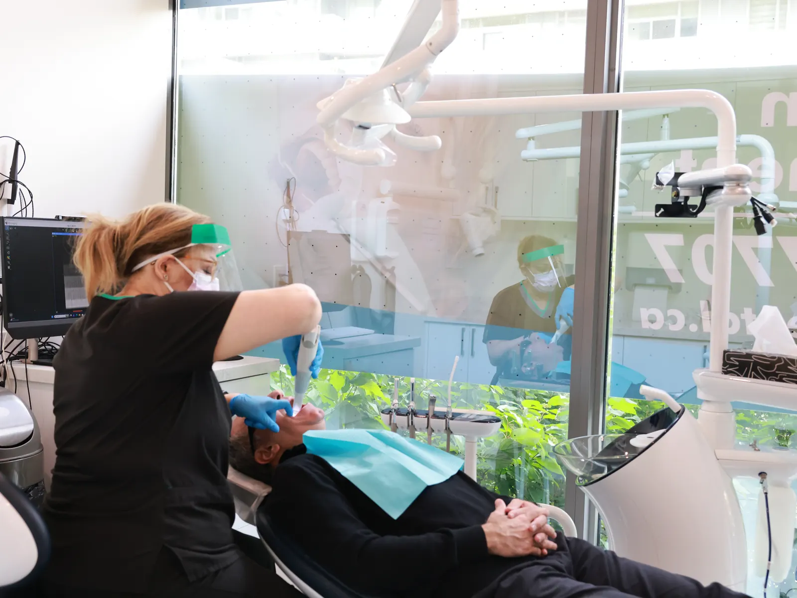 Hygienist treating a patient beside the clinic's bright window at Emerald Forest Dental Clinic in North York