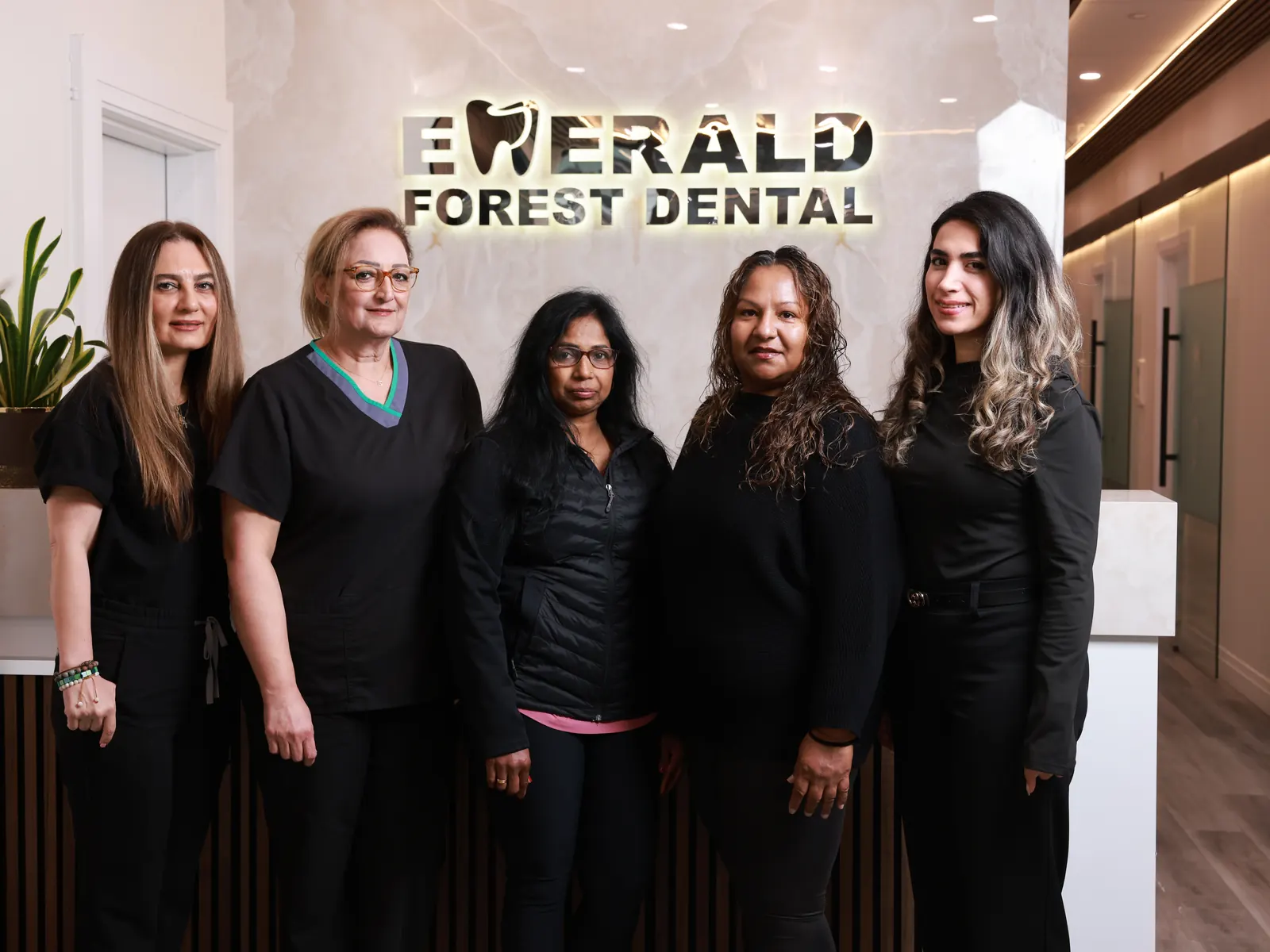 Five members of the Emerald Forest Dental Clinic team smiling in the reception area of the North York clinic